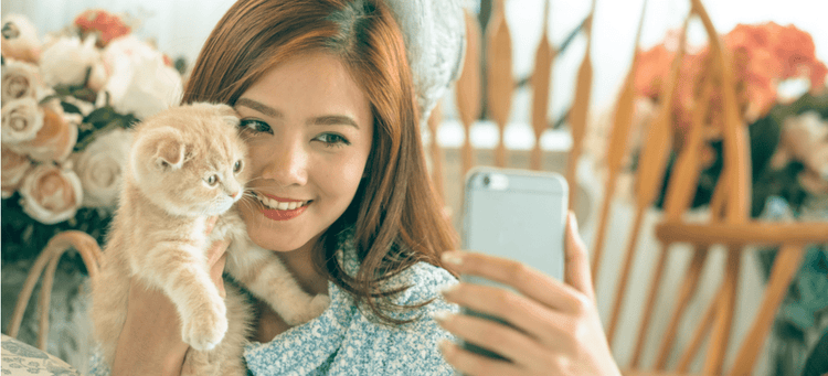 A girl takes a selfie with her cat for Instagram.