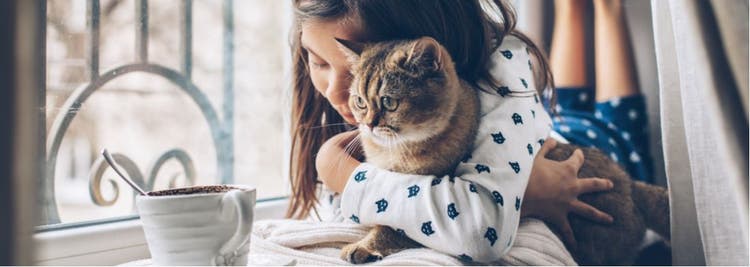 A child snuggling with her cat.