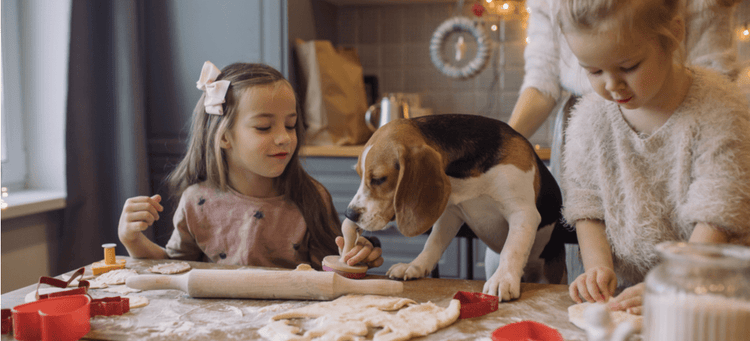 Kids and their dog making Christmas cookies.