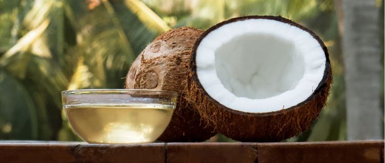Coconut oil and a coconut in front of palm trees.