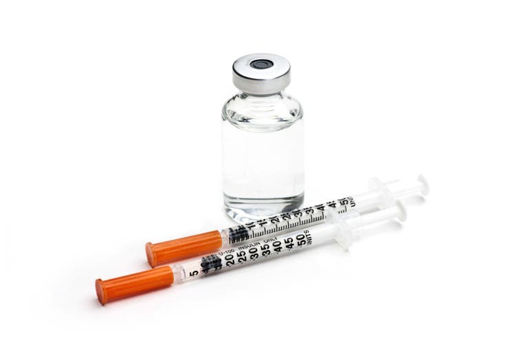 Insulin syringes and insulin bottle on white background.