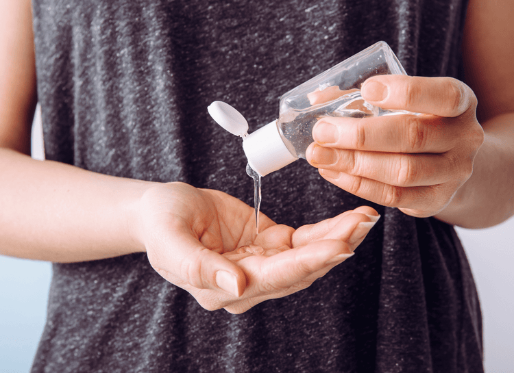 A woman pours hand sanitizer into her cupped hand.