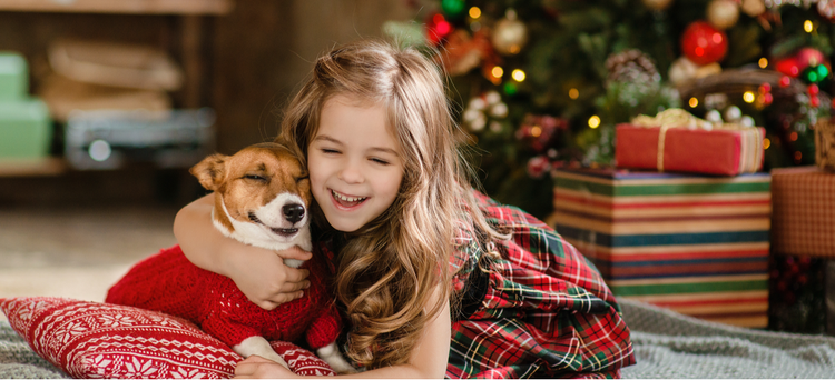 A young girl hugs her new Christmas dog.