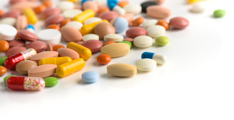 A collection of multi-colored pills on a white table.