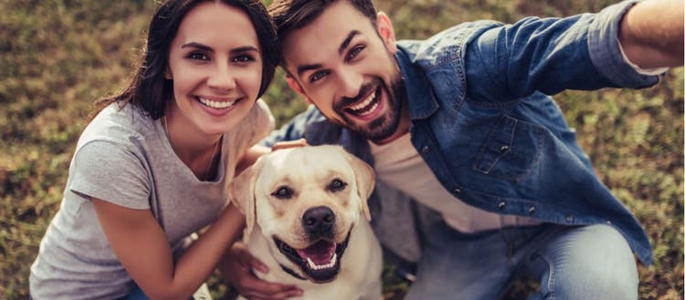A couple take a selfie with their dog.