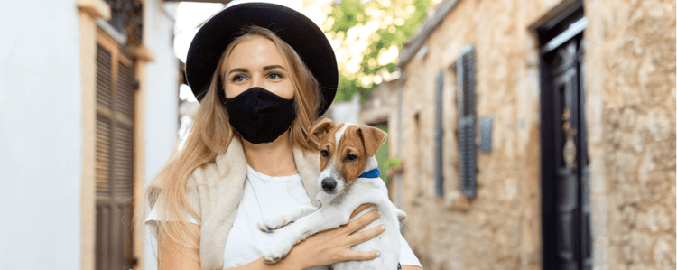 A woman carries her dog while wearing a surgical mask to prevent COVID-19 infection.