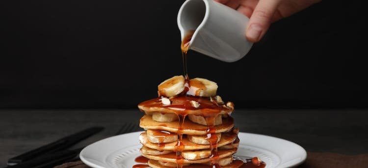 Pouring maple syrup over pancakes.