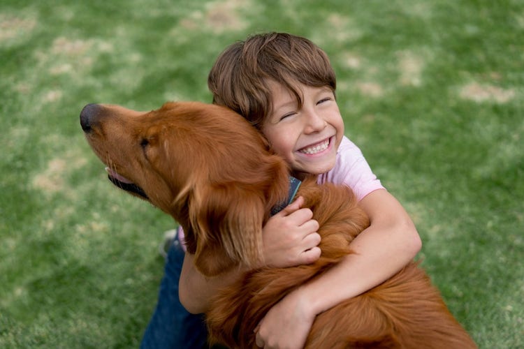 Young boy hugging his dog outside